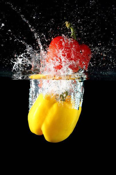 sweet pepper drop into water on black background. - Valokuva, kuva