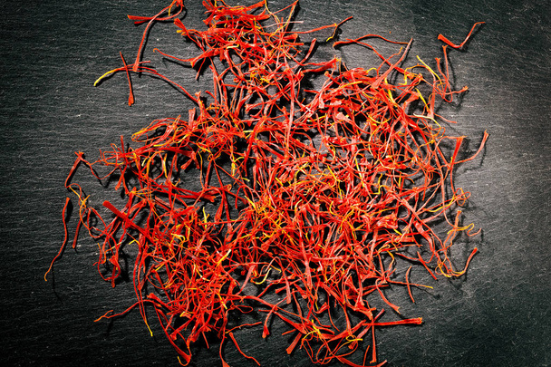 Heap of saffron threads on dark iron cast background - Foto, afbeelding