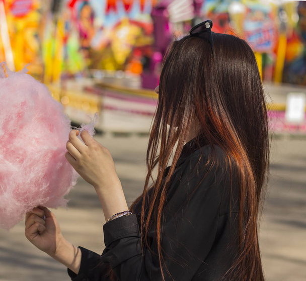 Young woman standing with pink cotton candy p in amusement Park - Photo, Image