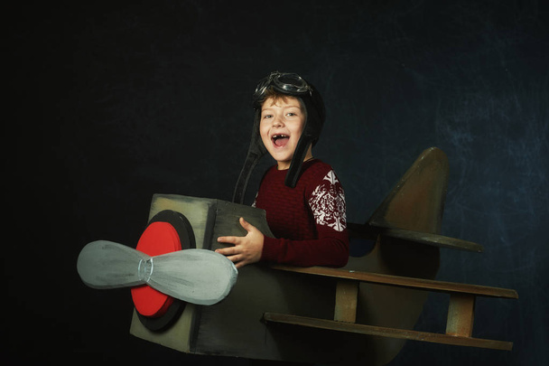 Niño jugando piloto de avión, niño jugando con avión sobre fondo oscuro
 - Foto, Imagen