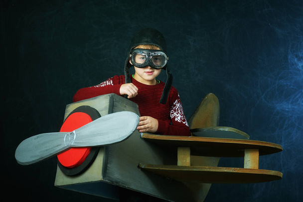 Little child playing airplane pilot, boy playing with airplane on dark background - Foto, immagini