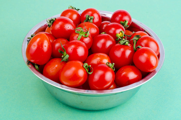 Mały czerwony dojrzałe pomidory cherry w misce na zielonym tle. Studio Photo - Zdjęcie, obraz