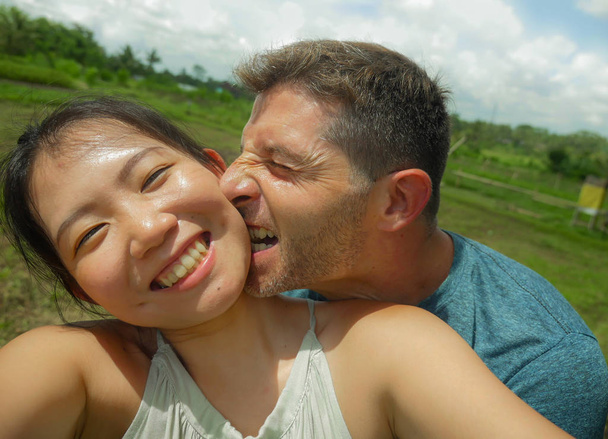 jovem bonito e feliz misto etnia casal bonito asiático chinês mulher e branco homem no amor tomando selfie imagem ao ar livre desfrutando romântico férias viagem em tropical lua de mel férias
 - Foto, Imagem
