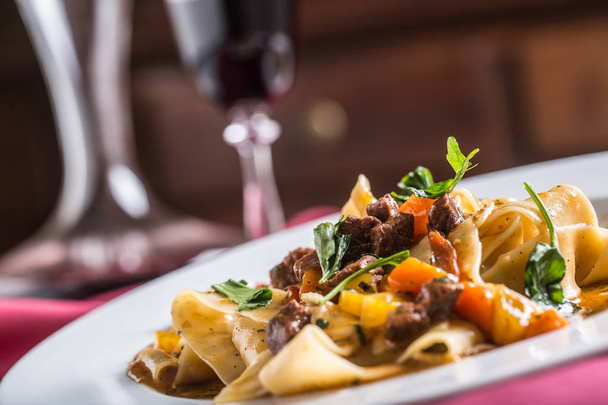 Idalian pasta pappardelle with beef ragout on white plate and red wine. - Photo, Image