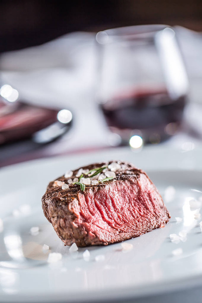Beef tenderloin steak on white plate and red wine in pub or restaurant. - 写真・画像