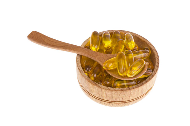 Gele vitamine zachte gelatine capsules met vette drug en voedingssupplement, houten lepels, schep. Studio foto - Foto, afbeelding