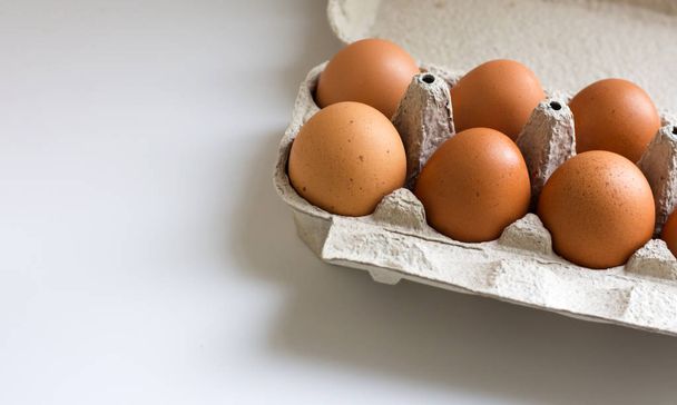 Pack of farm chicken eggs in cardboard container on white. Top view. - Valokuva, kuva