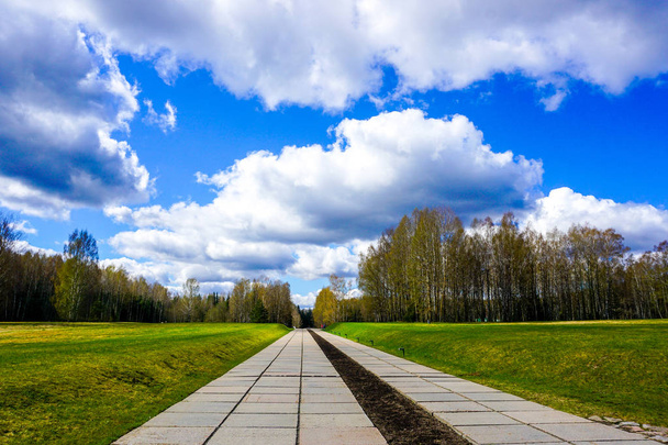 Khatyn Memorial Complejo Salir Camino con árboles Hierba y cielo azul con nubes
 - Foto, imagen