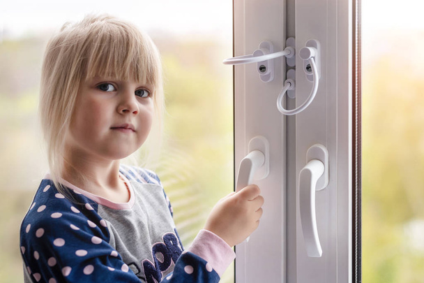 Küçük şirin bebek kız yüksek kule binasında dairede penceresini açmak çalışıyor. Çocuk pencere kilit koruma. Kablo güvenlik görevlisi açılış pencere çocuk tarafından önlemek. Düşen kaza önleme - Fotoğraf, Görsel