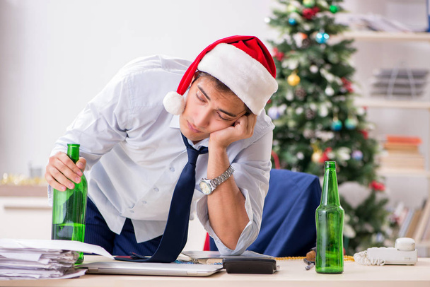 Jonge knappe werknemer vieren Kerstmis op werkplek  - Foto, afbeelding