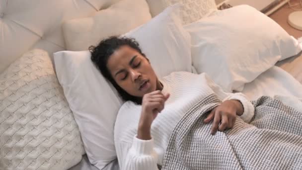 Vista superior de la joven enferma africana tosiendo mientras duerme en la cama
 - Imágenes, Vídeo