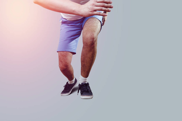 Athlete on the move. The man during the start to run, readiness for jogging. The concept of sport, warm-up before the run. Man isolated on a bright gray background. - Photo, Image