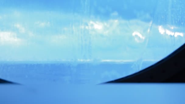 Do skleněné kulaté okénkem lodi tekoucí vody, tryskající z vln. Modré pozadí - Záběry, video