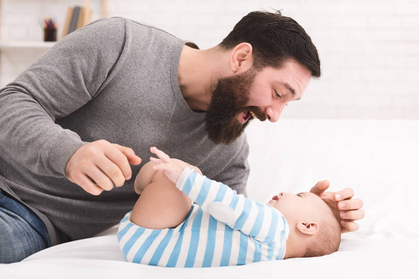 Pai cócegas e aconchegar seu filho bebê
 - Foto, Imagem