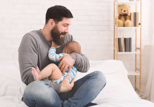 Neugeborenes weint in Händen des Vaters im Bett - Foto, Bild