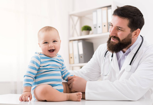 Adorable baby sitting with doctor at clinic - Photo, Image