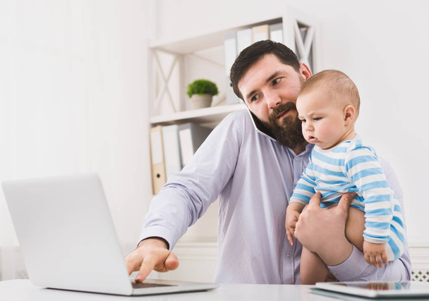 Papá de negocios trabajando en la oficina con el bebé hijo
 - Foto, Imagen
