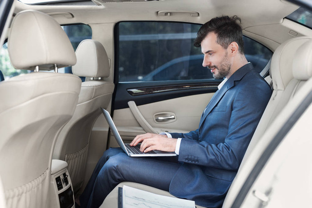 Business man working on laptop in car - Фото, зображення