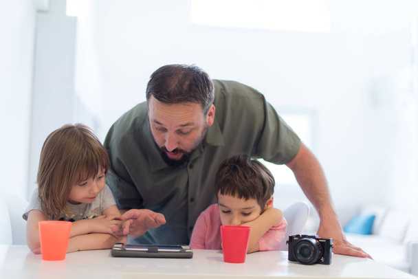 single father at home with two kids playing games and giving education lessons on tablet  computer at modern home - Фото, зображення