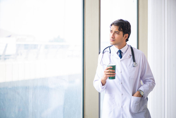 Молодий красивий лікар стоїть біля вікна
  - Фото, зображення