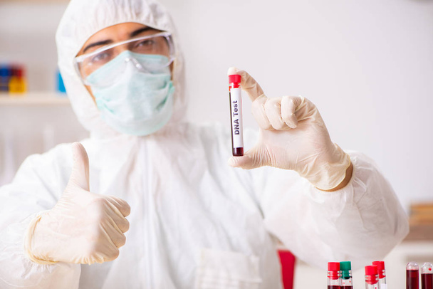 Νεαρός όμορφος βοηθός εργαστηρίου που εξετάζει δείγματα αίματος στο νοσοκομείο  - Φωτογραφία, εικόνα
