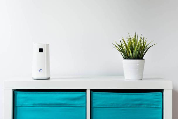 Ionizer stands on a white shelf on a white background. Air purifier at work, taking care of the comfort of residents, employees in the office. Getting rid of dust, smog, viruses, fungi from the air. - Photo, Image
