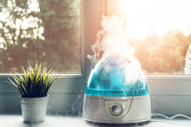 Air humidifier during work. The white humidifier moistens dry air. Improving the comfort of living in the home, apartment. Improving the well-being of people. - Photo, Image