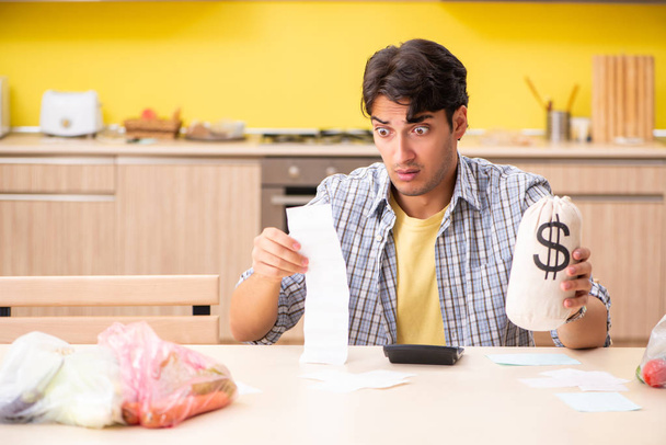 Mladý muž počítá výdaje na zeleninu v kuchyni  - Fotografie, Obrázek