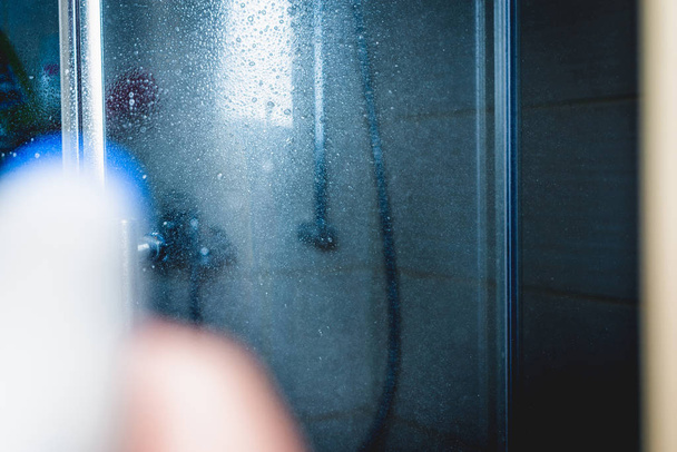 Пылесосить плитку на кухне, в ванной. Мужчина протирает пол на кухне, используя серый пылесос
. - Фото, изображение