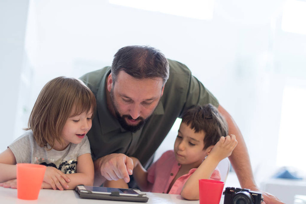 single father at home with two kids playing games and giving education lessons on tablet  computer at modern home - Photo, Image