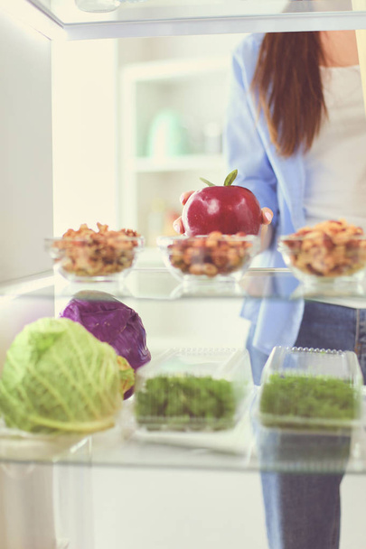 Portrait of female standing near open fridge full of healthy food, vegetables and fruits. - Fotoğraf, Görsel