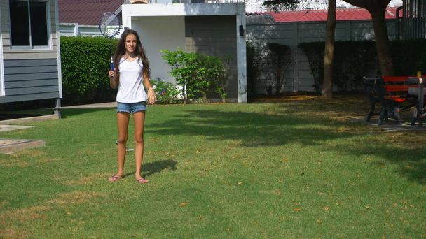 A teenager boy and girl play badminton on a green lawn in the backyard of their home - Foto, immagini