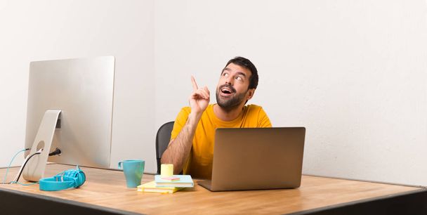 Mężczyzna pracujący z laptot w biurze myślenie pomysł wskazując palcem w - Zdjęcie, obraz
