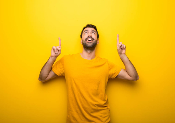 Ο άνθρωπος σε απομονωμένες δονούμενο χρώμα κίτρινο δείχνοντας με το δάχτυλο δεικτών μια μεγάλη ιδέα - Φωτογραφία, εικόνα