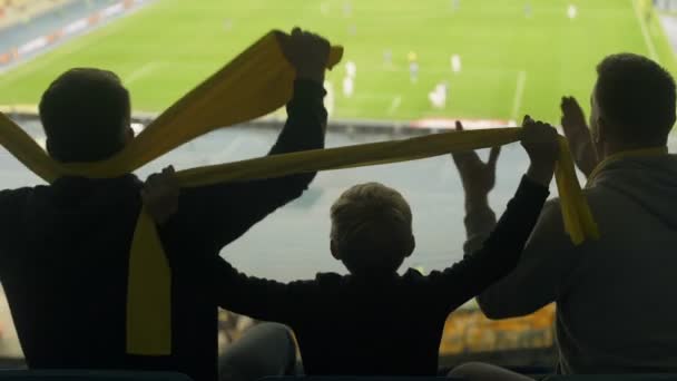 Miespuoliset ystävät lapsen kanssa katsomassa jalkapalloa stadionilla, adrenaliinia ja tunteita
 - Materiaali, video