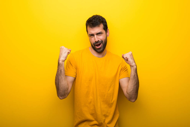 Ο άνθρωπος σε απομονωμένες δονούμενο χρώμα κίτρινο γιορτάζει μια νίκη - Φωτογραφία, εικόνα