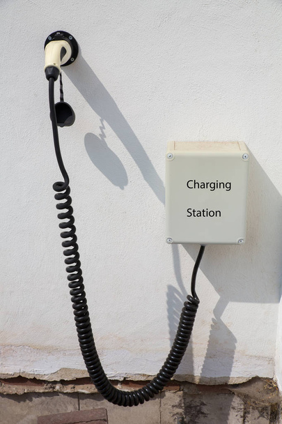 Точка зарядки для электромобиля на белой стене дома
 - Фото, изображение