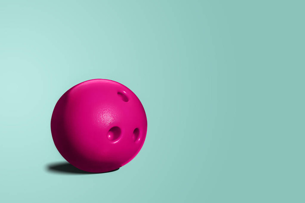 Рожева куля для боулінгу. Іграшковий боулінг-куля рожевого кольору на синьому, бірюзовому пастельному фоні. Мінімалістична концепція, абстрактна. Концепція веселощів, зустріч з друзями
. - Фото, зображення