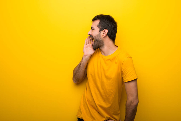 Man on isolated vibrant yellow color shouting with mouth wide open to the lateral - Photo, Image