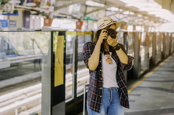 Belle donne stanno scattando foto in attesa del treno con i bagagli, Con concetto di svago, avventura e pianificatore di viaggio in treno, Durante le vacanze estive da soli
. - Foto, immagini