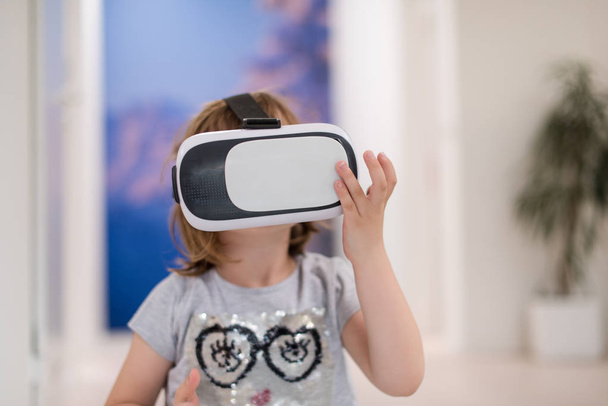 little gir at home wearing vr glasses putting hands up and playing games - Photo, image