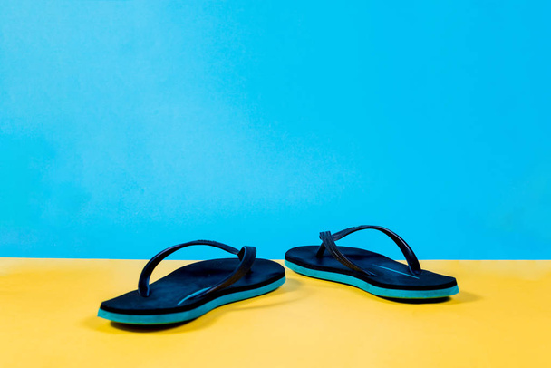 Zwarte en groene slippers, zomer set. De zomer is komende concept. Minimalistische stijl, minimalistische fotografie. Geel, roze en blauw pastel kleuren achtergrond. - Foto, afbeelding