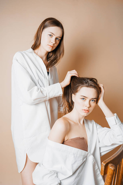 Mode-Modelle zwei Schwestern Zwillinge schöne nackte Mädchen, die in die Kamera isoliert auf beigem Hintergrund  - Foto, Bild