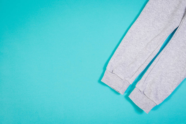 Top view of sweat pants on turquoise pastel background. Children's sweatpants with visible two legs. - Photo, Image