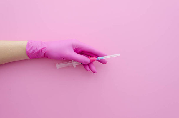 Ženská ruka v růžové latexové rukavice držící píchnutí injekční stříkačky - Fotografie, Obrázek