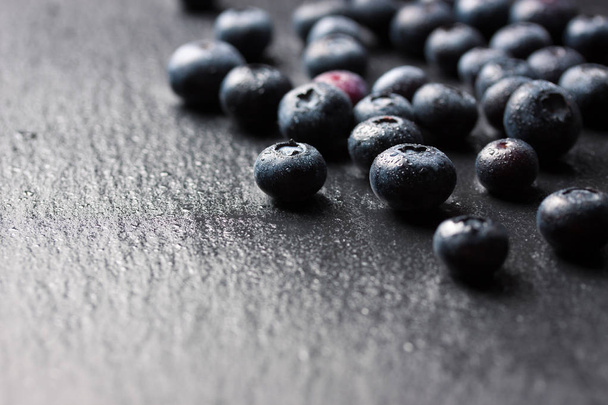Closeup of fresh ripe blueberries on a black stone background with copy space, selective focu - Photo, Image