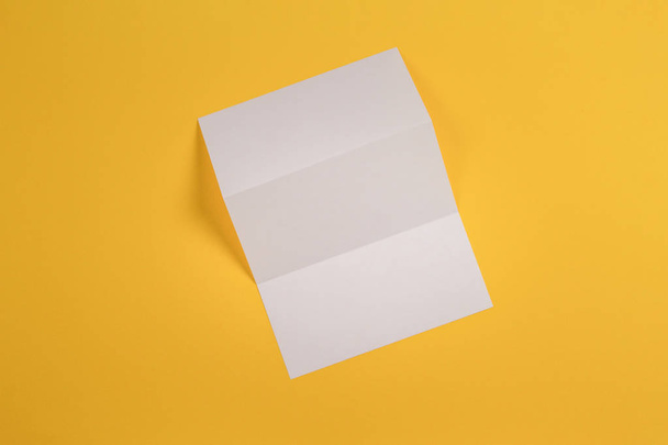空白の白いトリのモックアップは、黄色の背景に小冊子パンフレットを折る - 写真・画像