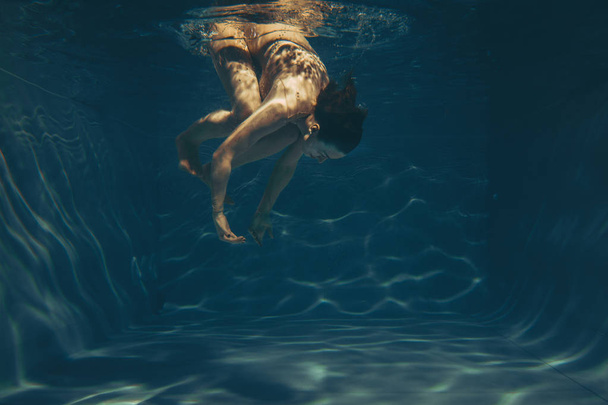 Niedliche sportliche Mädchen schwimmt unter Wasser als Freitaucher in schieren Jumpsuit allein - Foto, Bild