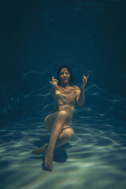 cute sporty girl swims underwater as a free diver in sheer jumpsuit alone - Foto, Imagem