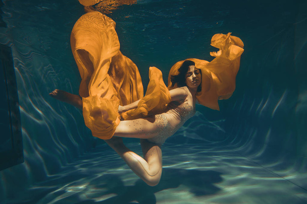 χαριτωμένο σπορ κορίτσι κολυμπάει υποβρύχια ως ένας ελεύθερος δύτης στην καθαρή ολόσωμη φόρμα μόνο - Φωτογραφία, εικόνα